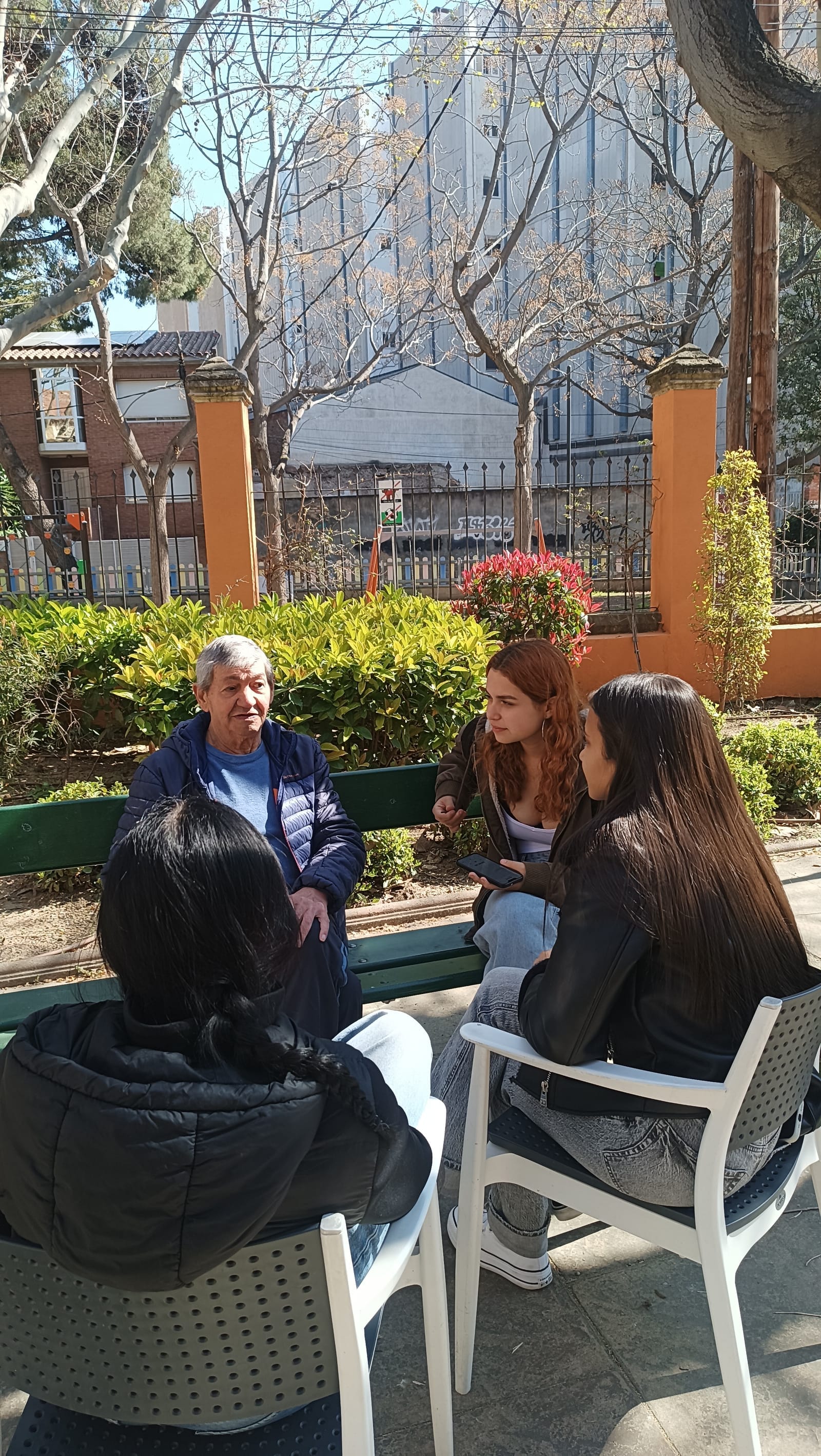 Un resident conversa amb un grup d'estudiants en un banc del jardí