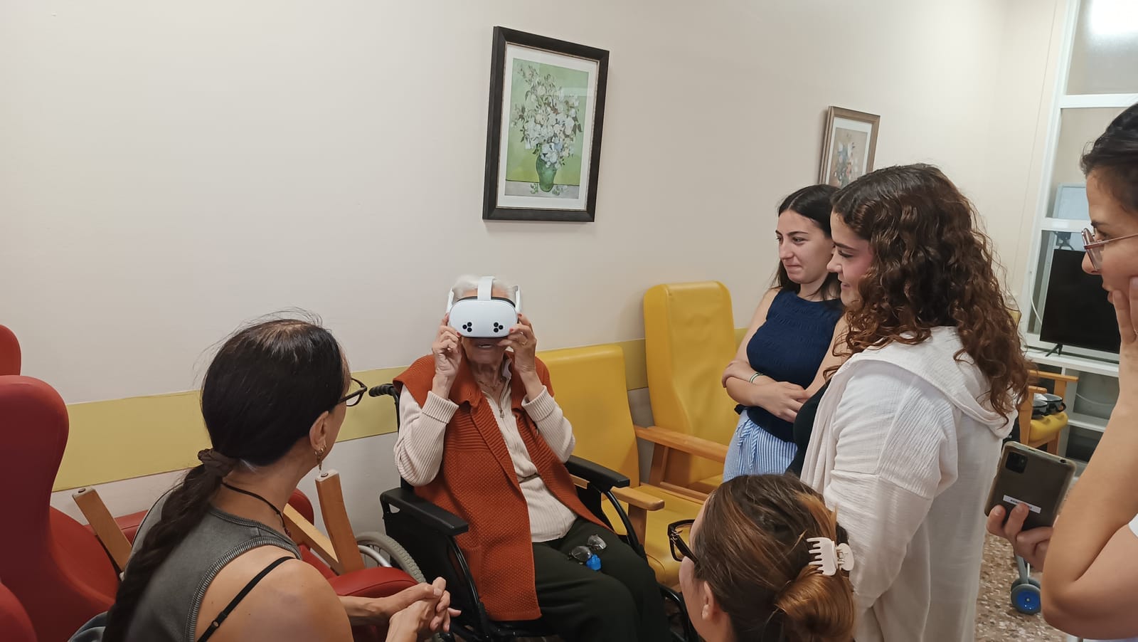Una resident es posa les ulleres de realitat virtual acompanyada de l'alumnat